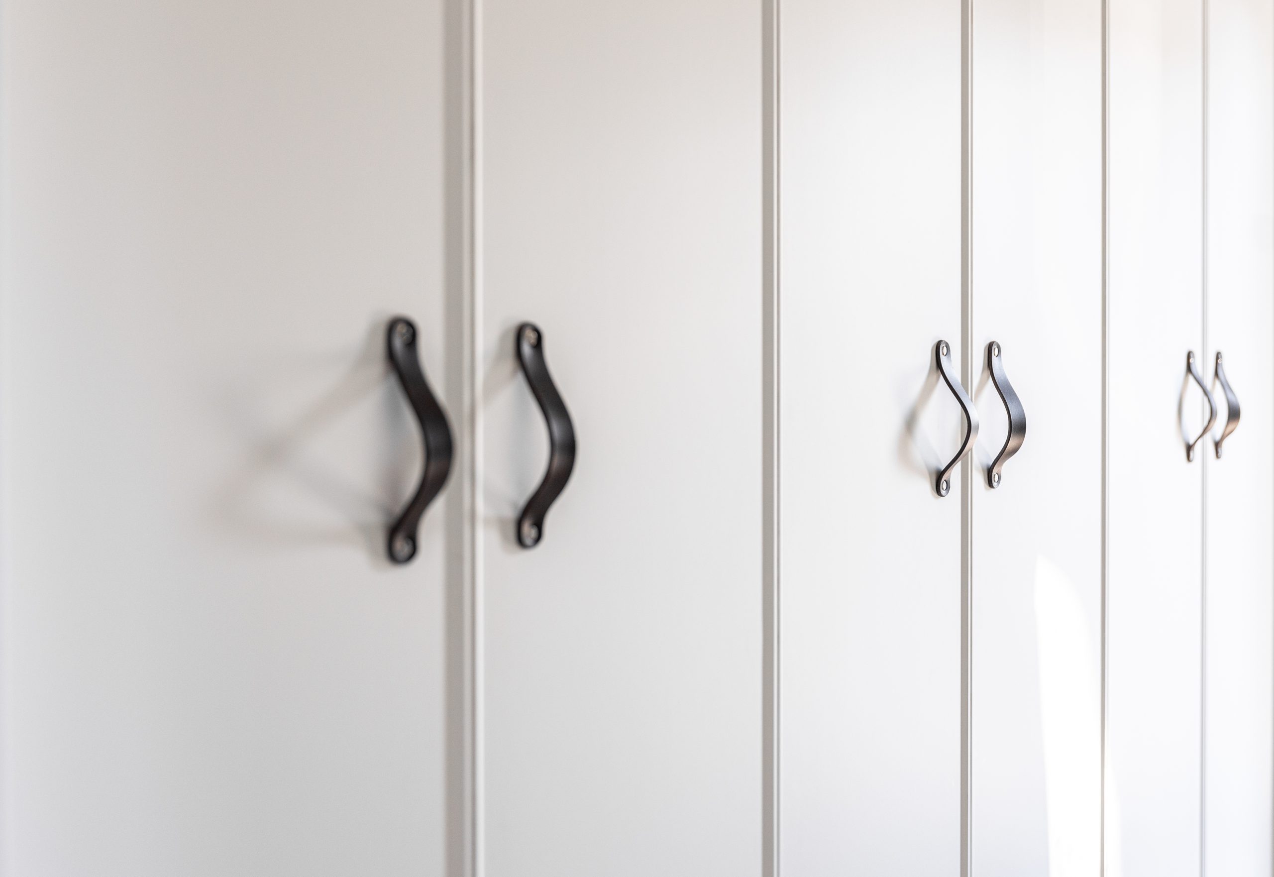close-up-of-minimalistic-white-furniture-with-black-handles-kitchen-cabinet-details